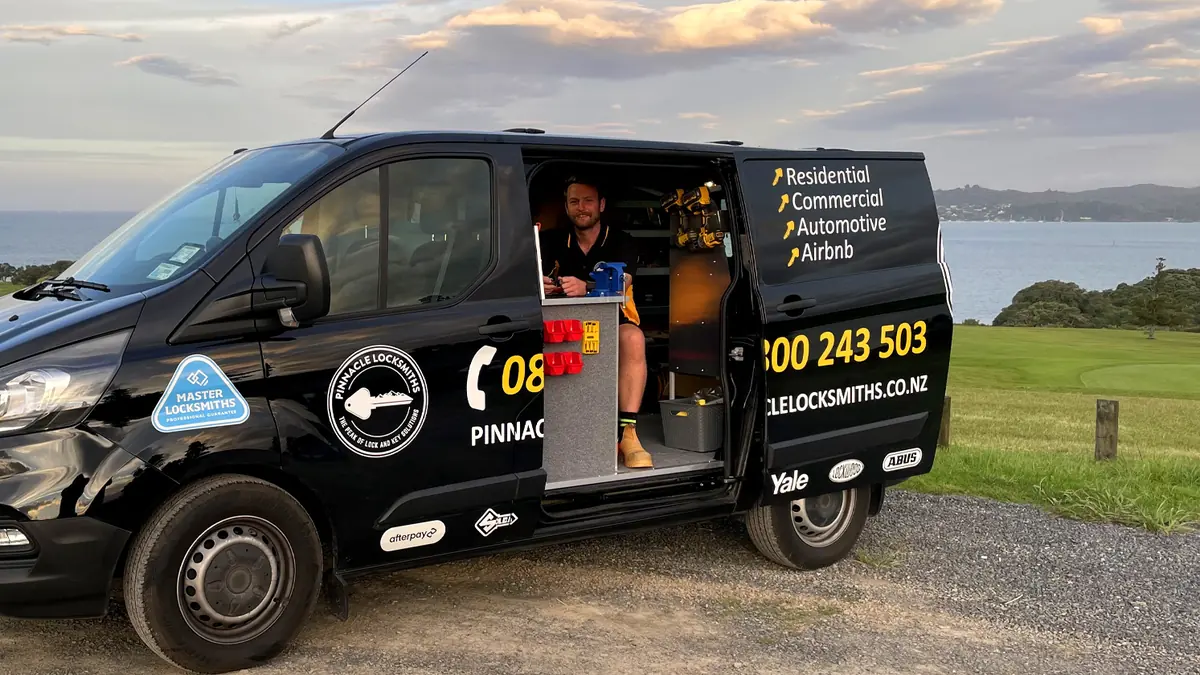 The Pinnacle Locksmiths van with its side door open beside the Northland coast, showing the fitted workshop inside